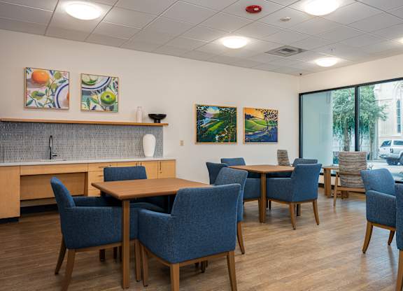 A room with a table and chairs and a painting on the wall.