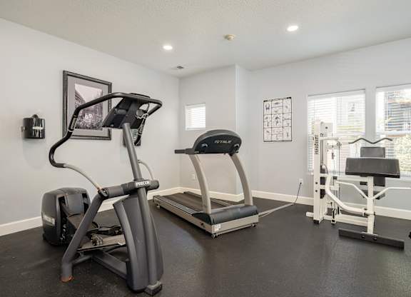 A home gym with a treadmill, elliptical trainer, and a stationary bike.