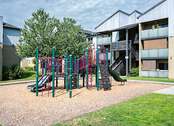 A playground with a green slide and a red and green play structure.