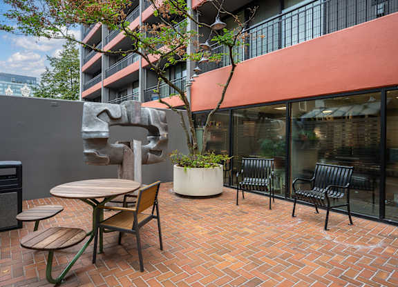 A patio with a table and chairs and a bench outside a building.