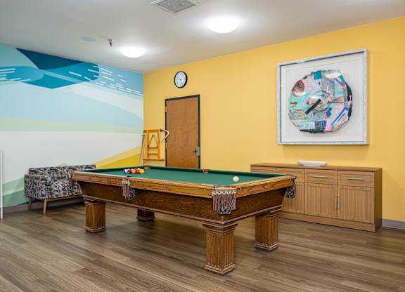 A pool table in a room with a clock on the wall.