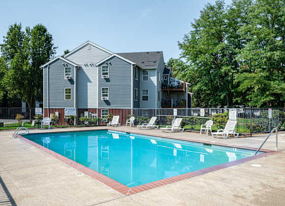 A swimming pool in front of a grey apartment building.