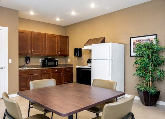 A kitchen with a table and chairs in the foreground and a refrigerator in the background.