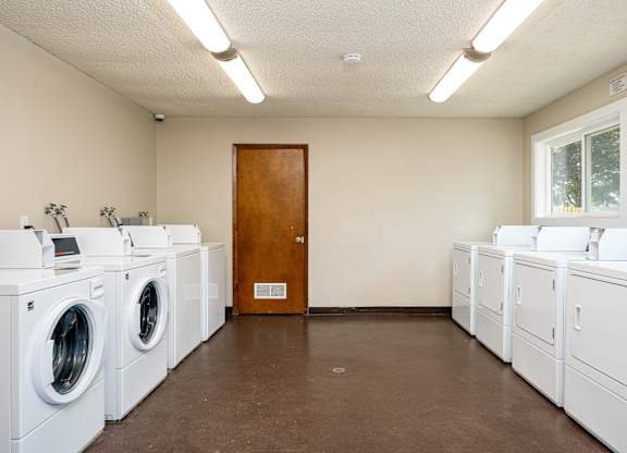 A laundromat with a row of washers and a door.