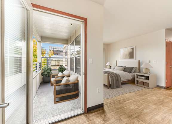 A bedroom with a bed, nightstand, and chair is shown through an open door.