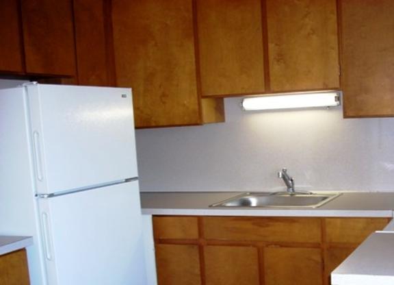 A kitchen with wooden cabinets and a white fridge.