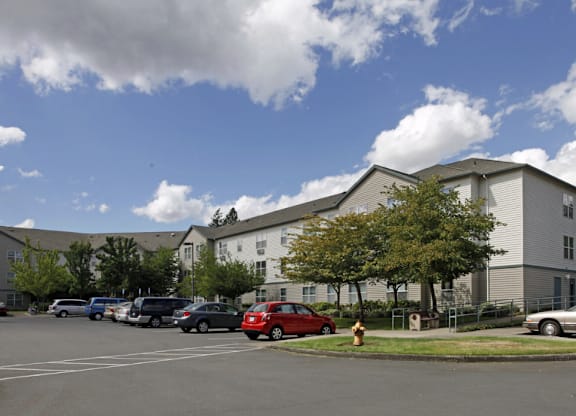 A parking lot with cars and a fire hydrant in front of a building.