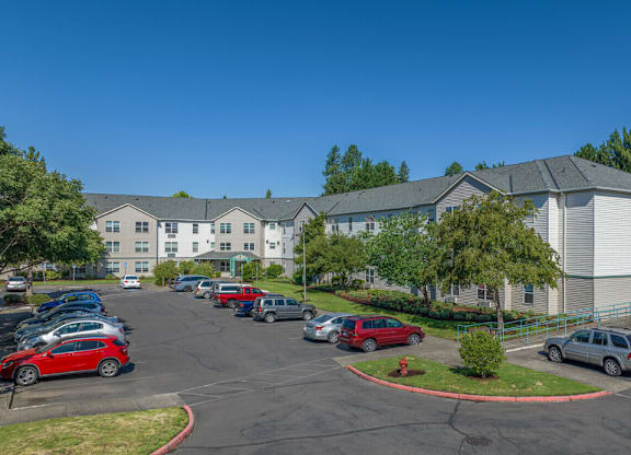 A parking lot in front of a building with cars parked.