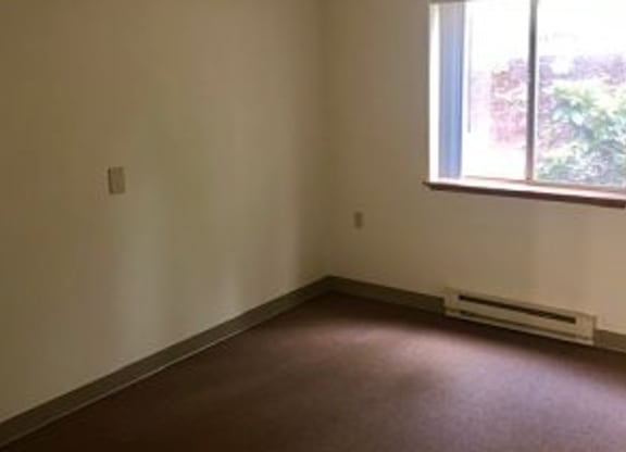 an empty room with a window and a ceiling fan