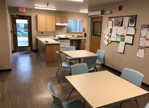 a multipurpose room with tables and chairs and a kitchen