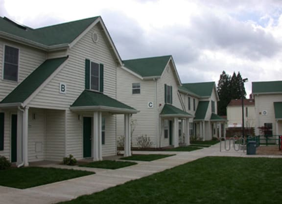 a row of white homes with green roofs