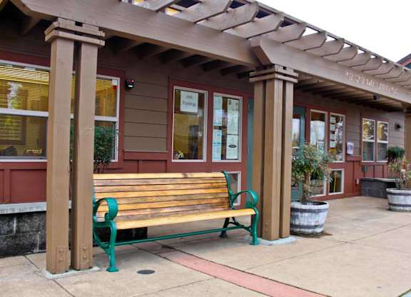 A wooden bench with green legs is in front of a building.