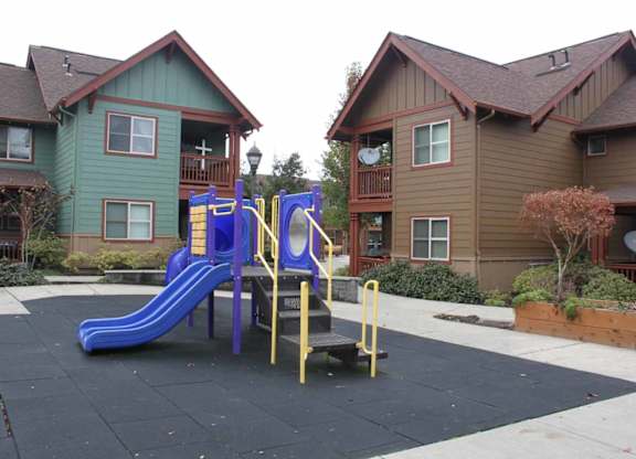 A playground with a blue slide and yellow railings.