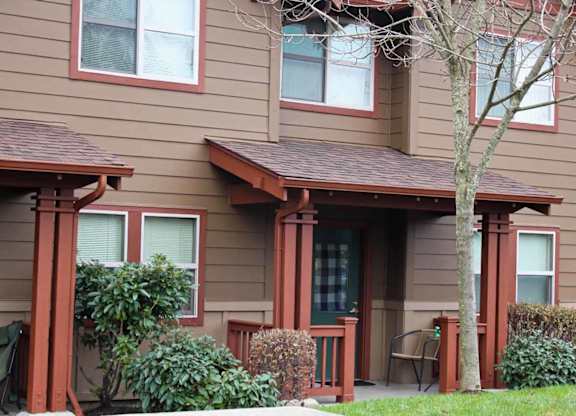 A brown house with a tree in front.