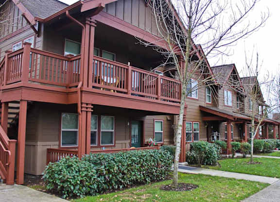 A brown building with a balcony and a tree in front.