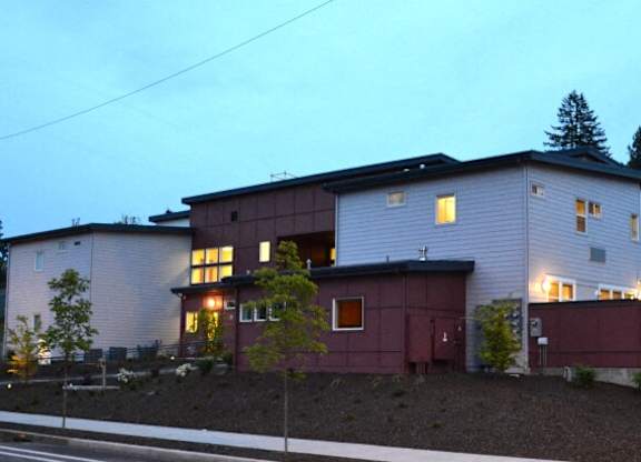 A house with a red garage door is lit up at dusk.