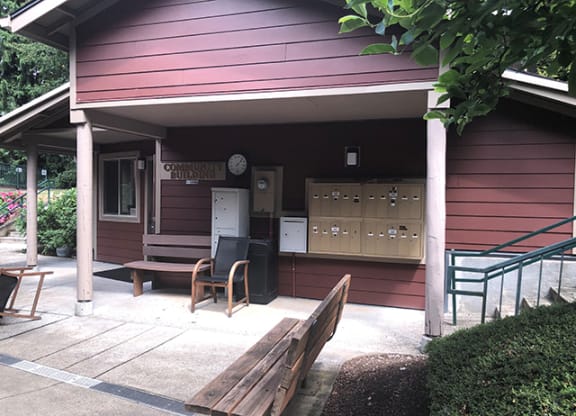 a porch in front of a red house with a wooden bench