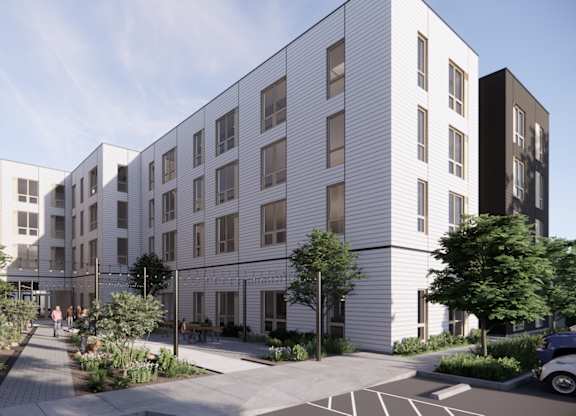 A modern building with a white facade and a tree-lined walkway in front.