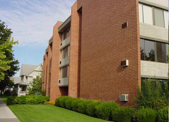 A red brick building with a green lawn in front.
