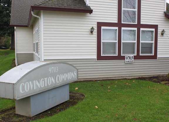 A sign for Covington Commons sits in front of a house.