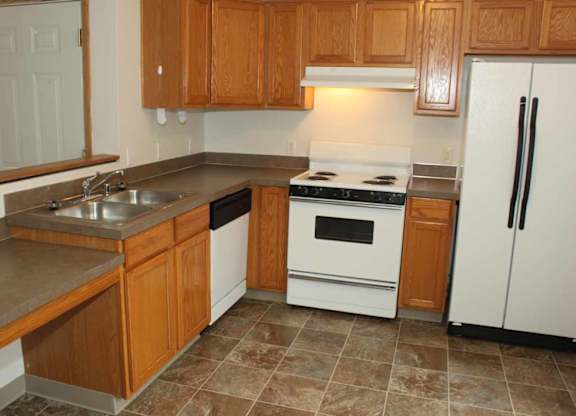A kitchen with wooden cabinets and a white stove top oven.