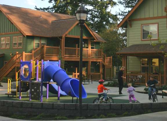 A playground with a purple slide in front of a green building.