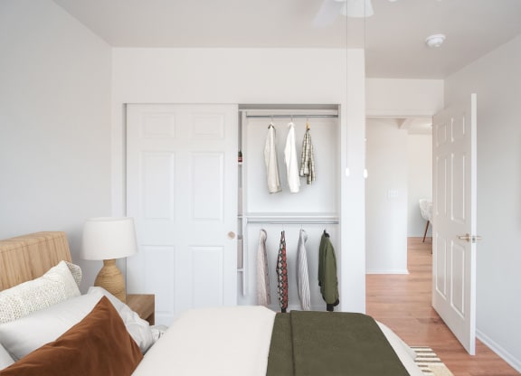 a bedroom with a bed and a closet with clothes