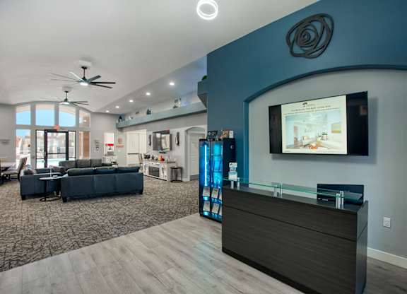 A modern living room with a dark sofa set and a flat screen TV mounted on the wall.