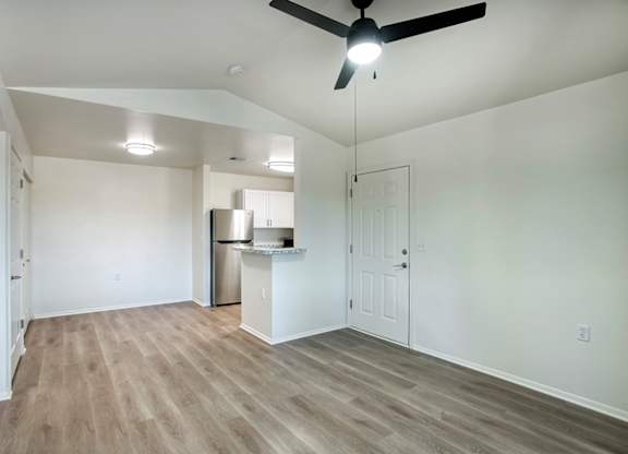 A room with a ceiling fan and a kitchenette.