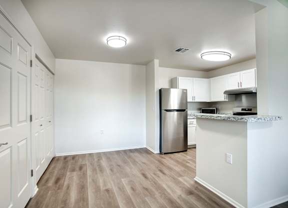 A kitchen with a refrigerator, cabinets, and a countertop.