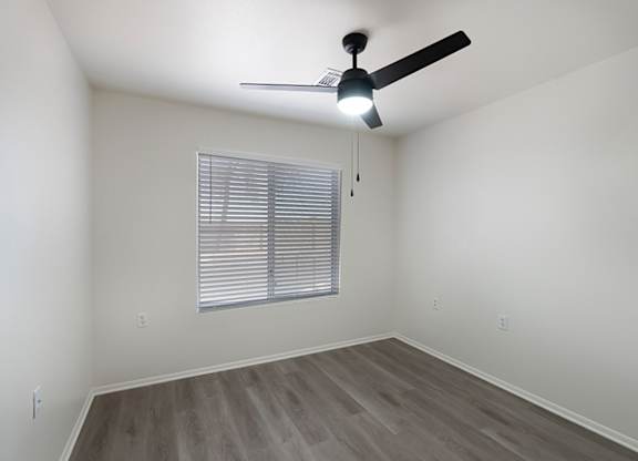 A room with a ceiling fan and a window with blinds.