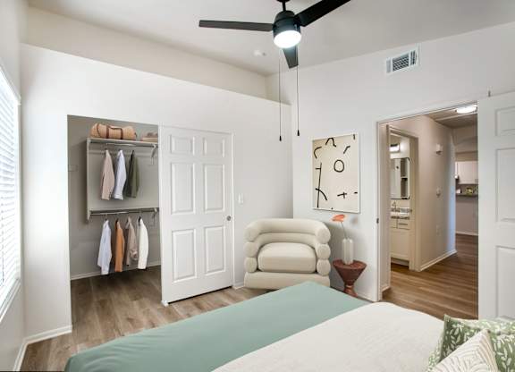 A bedroom with a bed, chair, and closet.