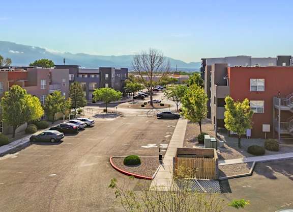 A parking lot with cars and apartment buildings in the background.