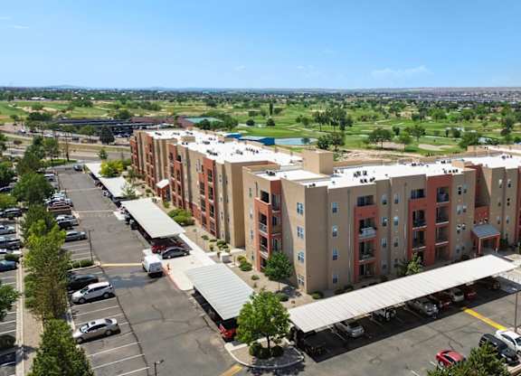 A large apartment complex with a parking lot in front.