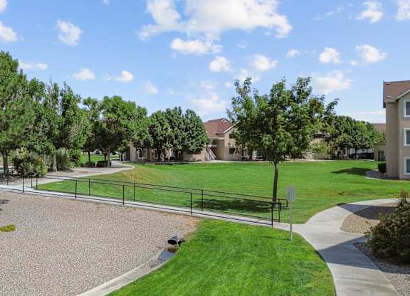 A park area with a gravel playground and a green lawn.