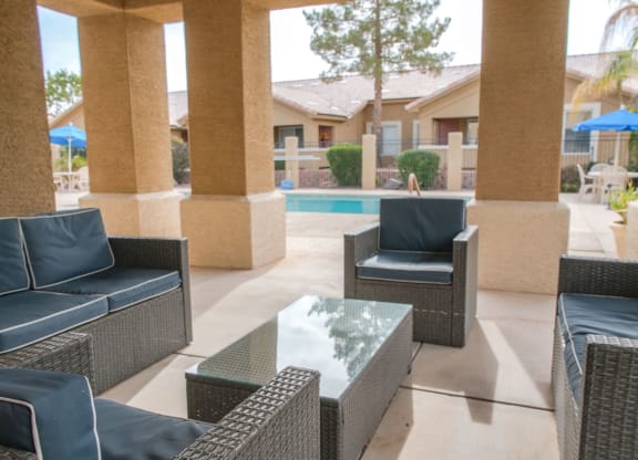 a patio with chairs and a table in front of a pool