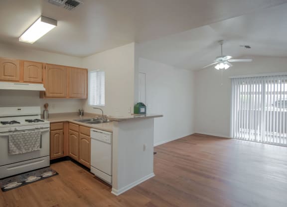 an empty kitchen and living room with wood flooring and a window