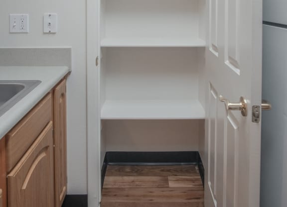 an empty kitchen with white shelves and a refrigerator