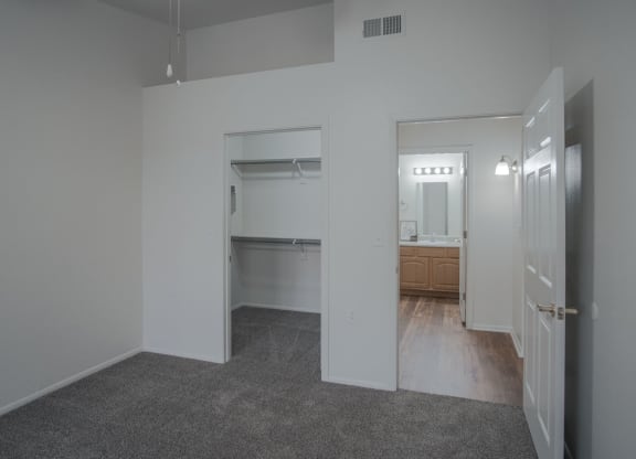 an empty living room with a hallway to a bathroom and a kitchen