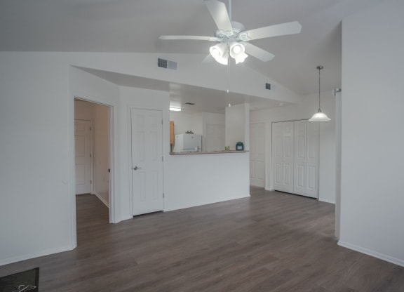 an empty living room with white walls and a ceiling fan
