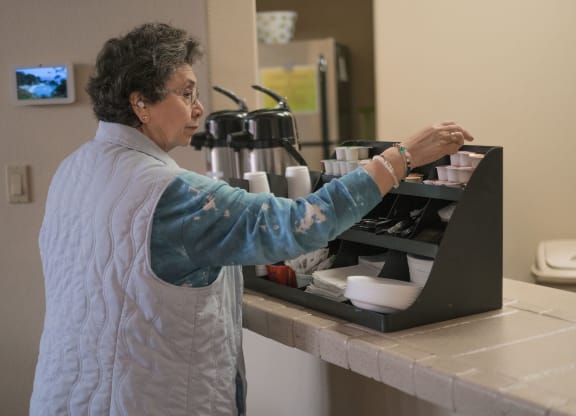 a woman prepares food in a kitchen on a laptop