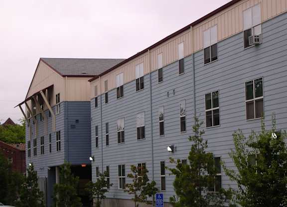 A large building with a blue and beige exterior and a carport.