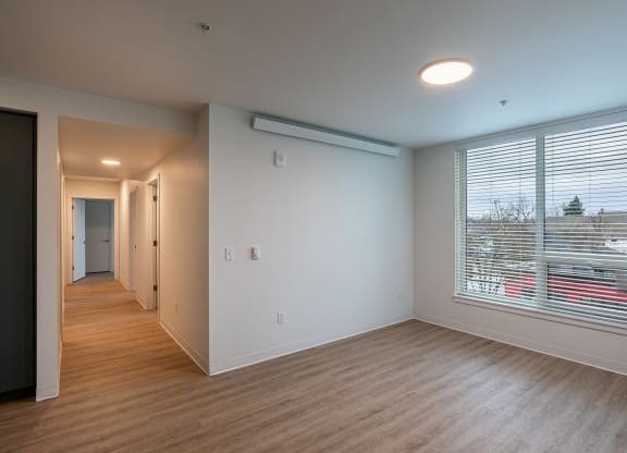 an empty living room with a large window and wood flooring