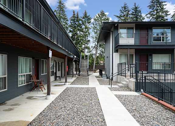 A long, narrow walkway with a black railing separates two buildings.