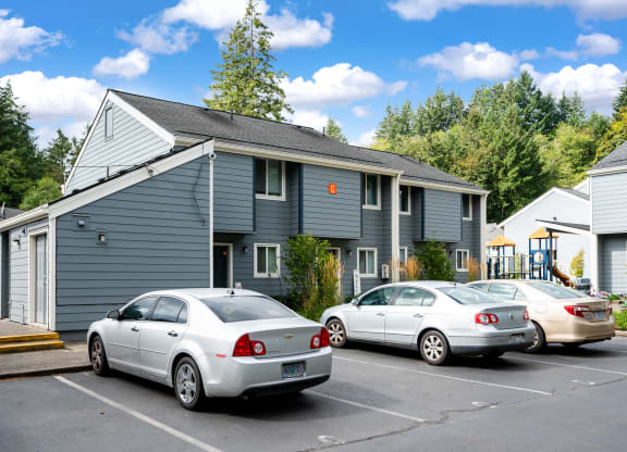 a gray house with cars parked in a parking lot