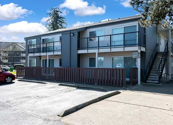 A modern two-story apartment building with a red car parked in front.