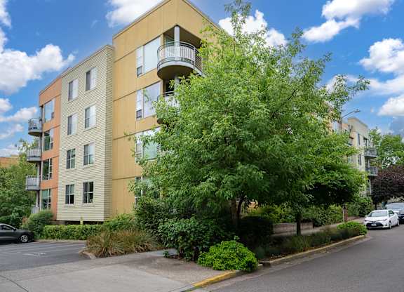 A modern apartment building with a balcony on the second floor.