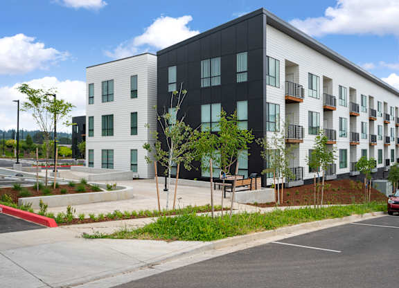 A modern apartment building with a red car driving by.