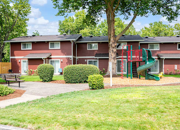 A red building with a green slide in the front yard.