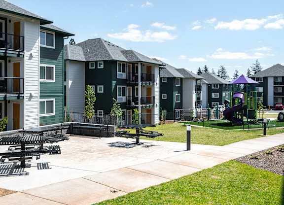 A playground area with a slide and a purple canopy is surrounded by apartment buildings.